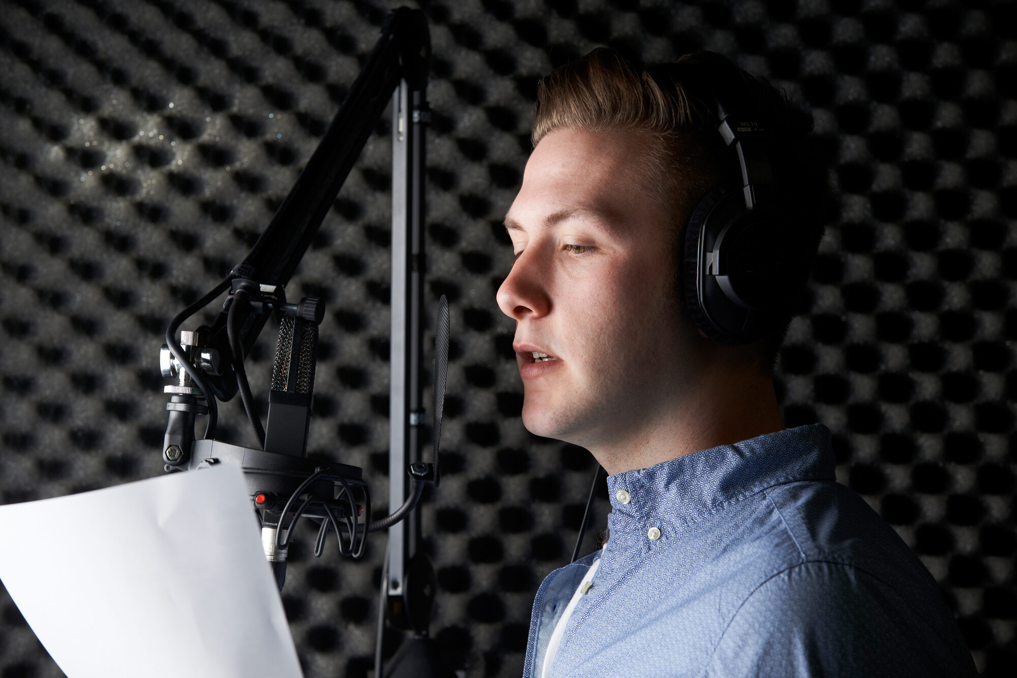 Man In Recording Studio Talking Into Microphone.
